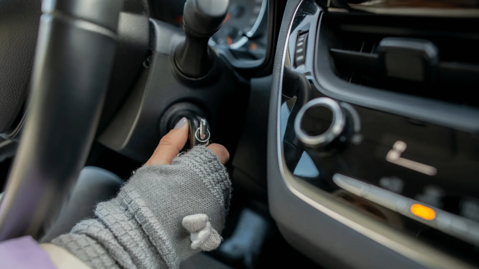 A person wearing gray fingerless gloves is turning a key in a cars ignition, with the dashboard and steering wheel visible in the background. EuroMechanic - Redline Automotive | Top Reviewed Auto Repair Shop in Scarborough | Visit EuroMechanic - Redline Automotive